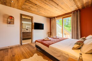A bedroom with a wooden ceiling, a bed with a red blanket, a flat-screen TV, and a window with curtains. - Chalet Haute Cime - Les Gets - Les Cornuts (Les Gets)