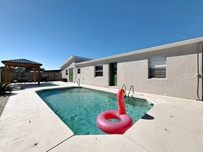 Ein Swimmingpool mit einem roten Schwimmschwan, einer überdachten Terrasse und einem Gebäude mit flachem Dach.