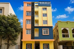 Un immeuble à plusieurs étages doté d’un escalier central, de balcons et d’un arbre au premier plan.