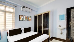 Ein Hotelzimmer mit einem Bett, einer Klimaanlage, einem Fenster mit Jalousien, einer Tür und einem wandmontierten Waschbecken.