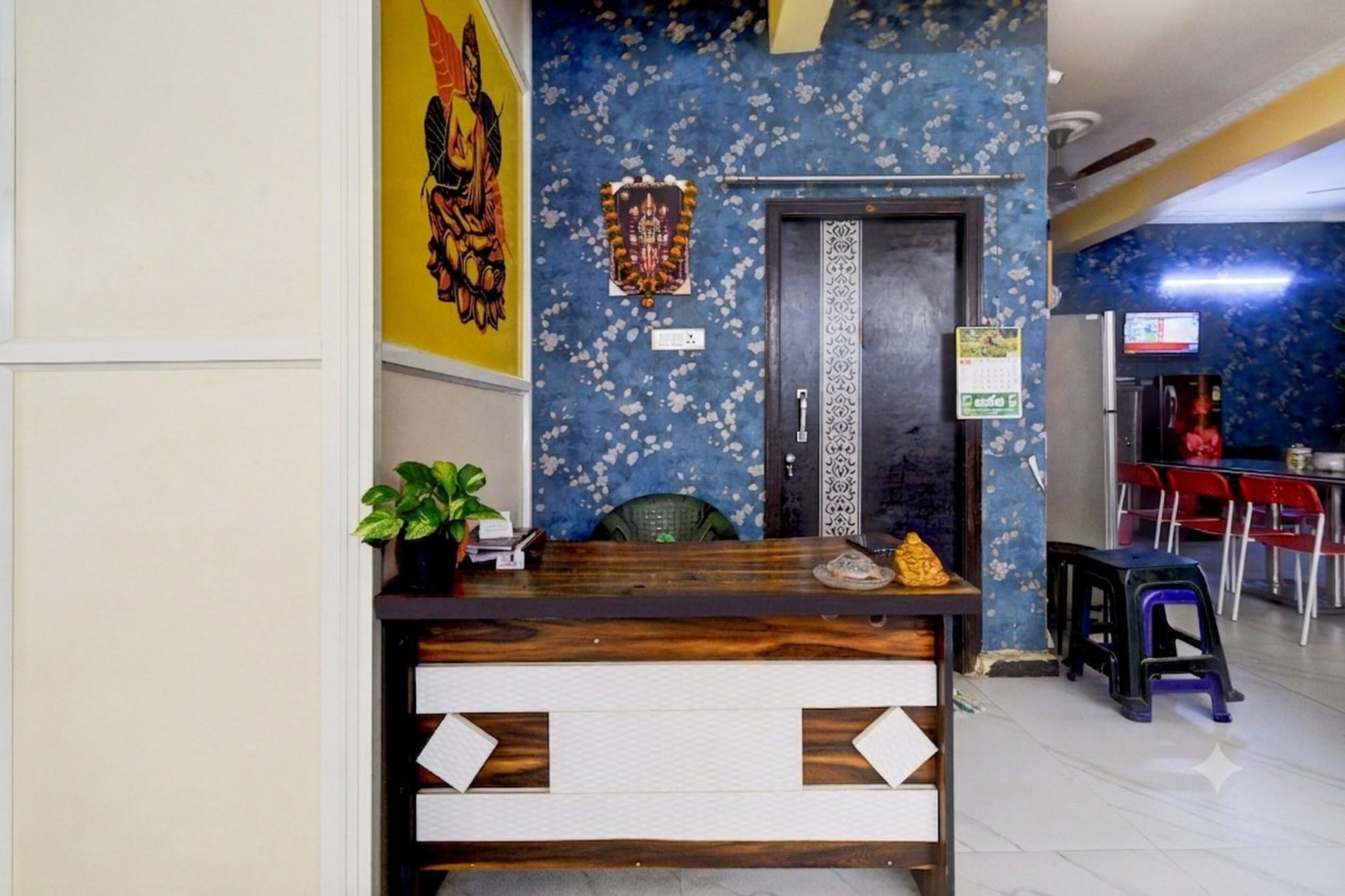 A reception desk with a plant, a calendar, and a small statue.