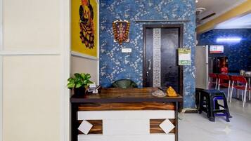 A reception desk with a plant, a calendar, and a small statue.
