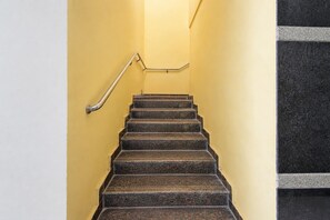 A staircase with a handrail, leading up to a landing with a black and white patterned wall. - Deluxe Room Sunidh (Hyderabad)