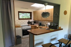 A compact kitchen with a stove, sink, and a window. There is a small trash bin and a bicycle in the corner. - Holiday home on the Baltic Sea (Glücksburg)