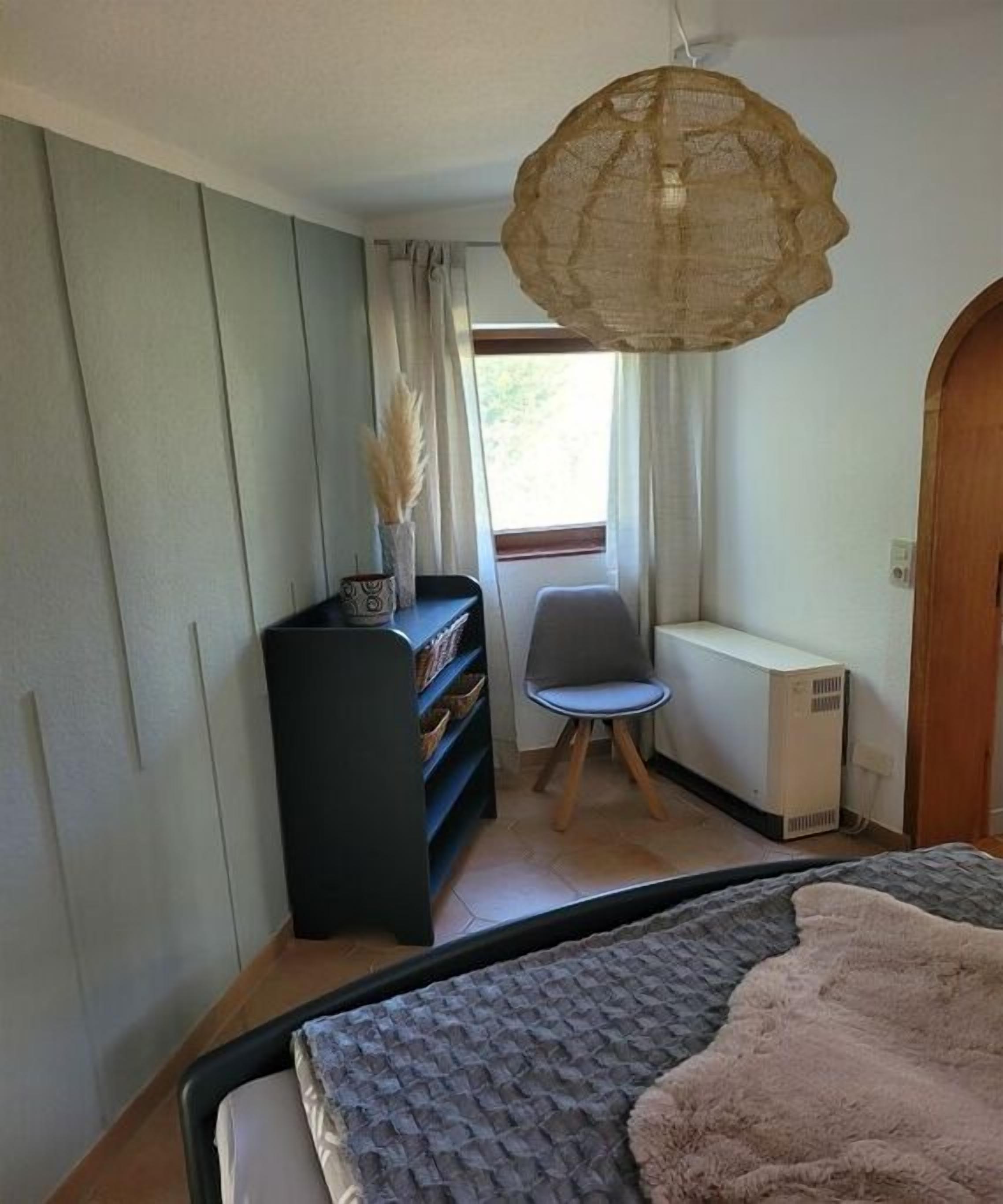 Une chambre à coucher avec un lit, une chaise, un radiateur et une bibliothèque.