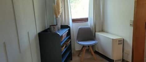 Une chambre à coucher avec un lit, une chaise, un radiateur et une bibliothèque.