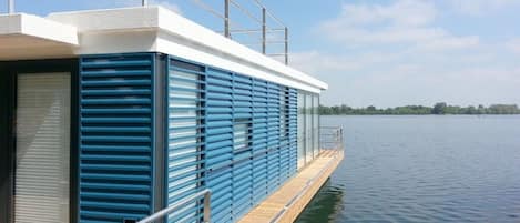 Un bateau moderne doté d’un pont plat, de garde-corps en métal et offrant une vue dégagée sur l’eau.