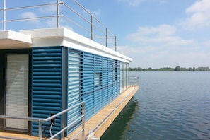 Un bateau moderne doté d’un pont plat, de garde-corps en métal et offrant une vue dégagée sur l’eau.