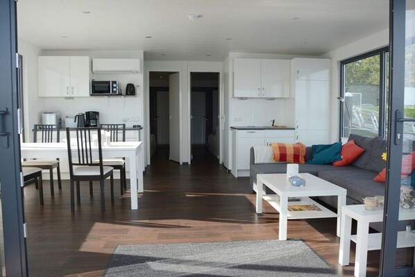 Un espace de vie moderne comprenant un coin repas, une kitchenette et un canapé agrémenté de coussins aux couleurs vives.