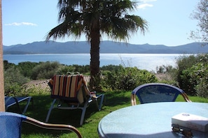 Un patio con mesa y sillas, con vista a un cuerpo de agua y montañas.