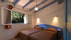Quarto com duas camas, janela com cortinas e luminária suspensa.
