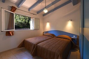 Un dormitorio con dos camas, una ventana con cortinas y una lámpara colgante.