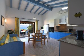 Una cocina moderna con armarios azules, un comedor con mesa y sillas, y vistas al exterior.