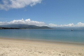 A beach with a clear sky, calm sea, and a boat in the distance. - Holiday home with 2 bedrooms (OLMETO PLAGE)