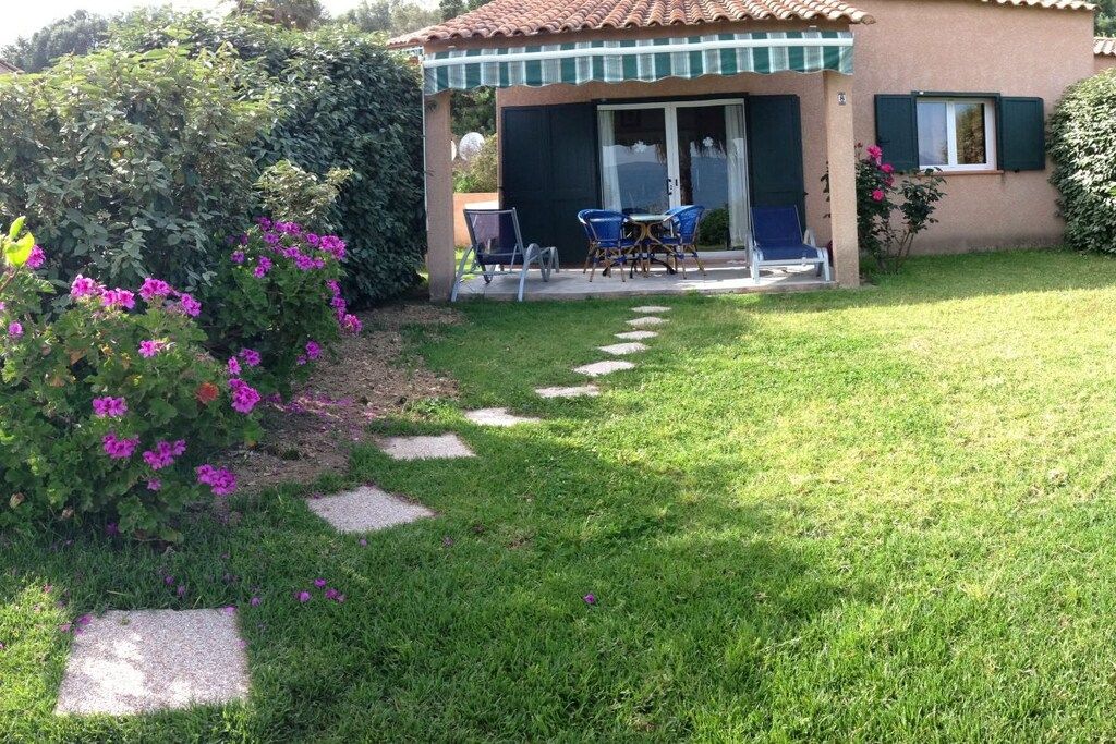 Une maison dotée d’un patio, d’un espace salon couvert et d’un jardin avec un chemin.