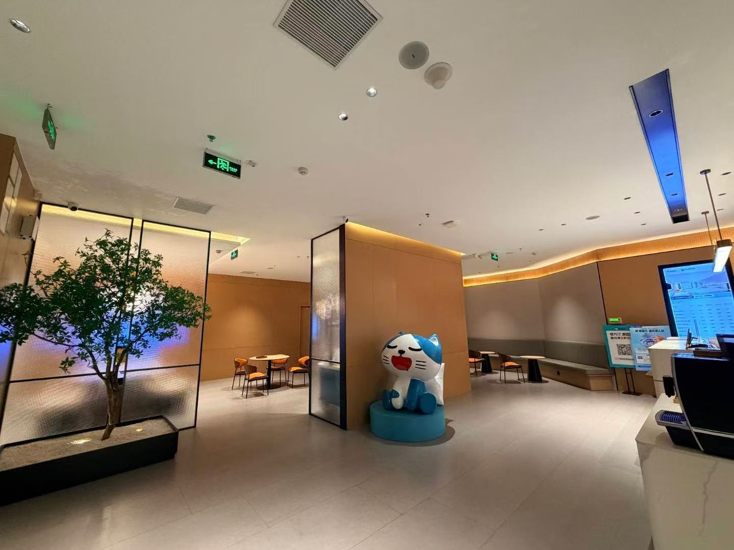 A modern hotel lobby with a reception desk, seating area, and a decorative cat statue.