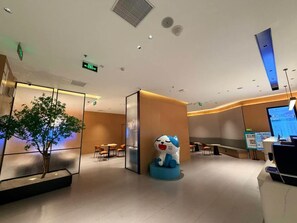A modern hotel lobby with a reception desk, seating area, and a decorative cat statue. - City Comfort Inn (Guangzhou)