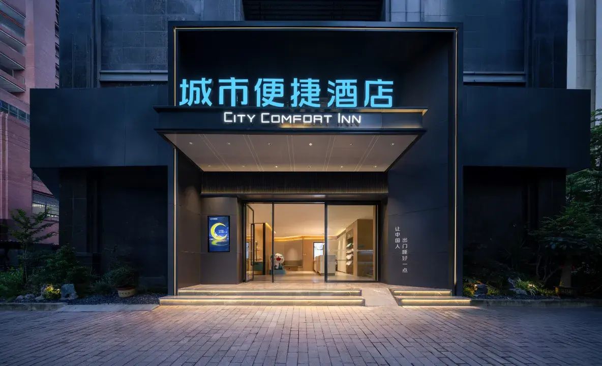 The exterior of the City Comfort Inn with a modern facade, glass entrance, and illuminated signage.