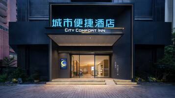 The exterior of the City Comfort Inn with a modern facade, glass entrance, and illuminated signage.
