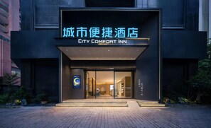 The exterior of the City Comfort Inn with a modern facade, glass entrance, and illuminated signage.