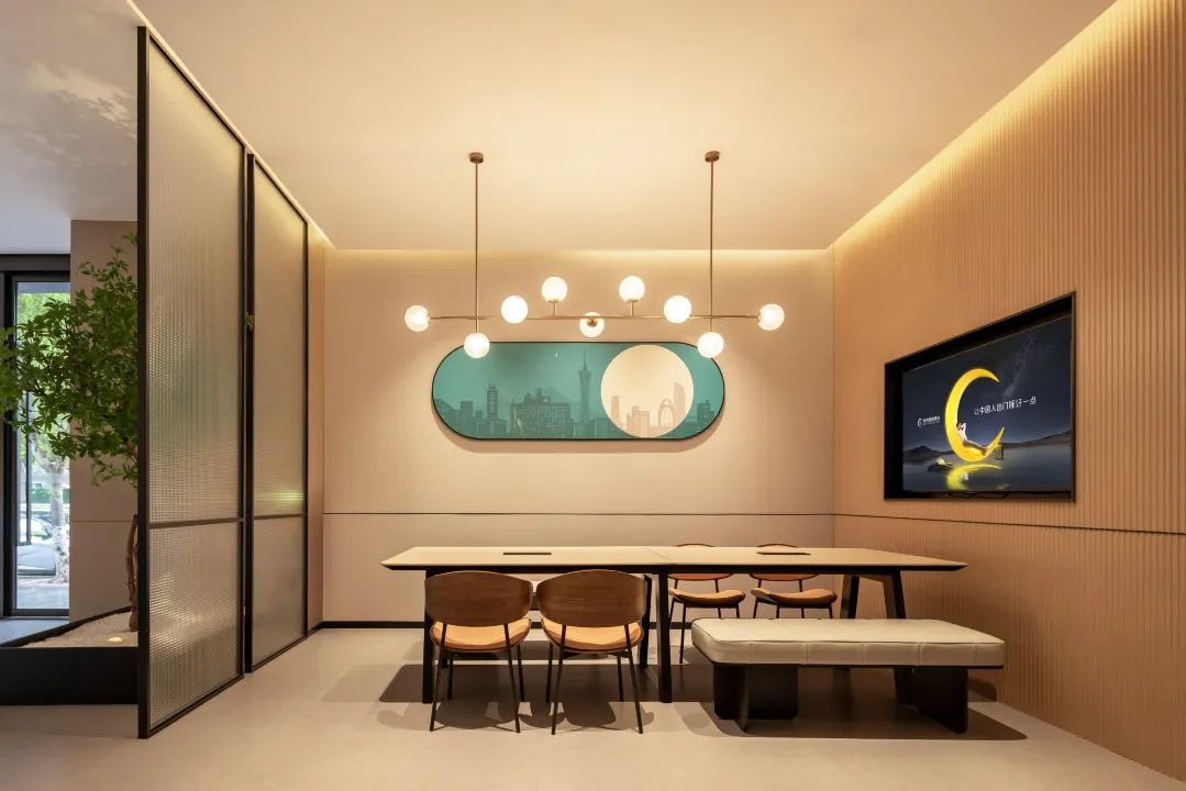 A modern conference room with a long table, chairs, a bench, a cityscape artwork, and a television screen.