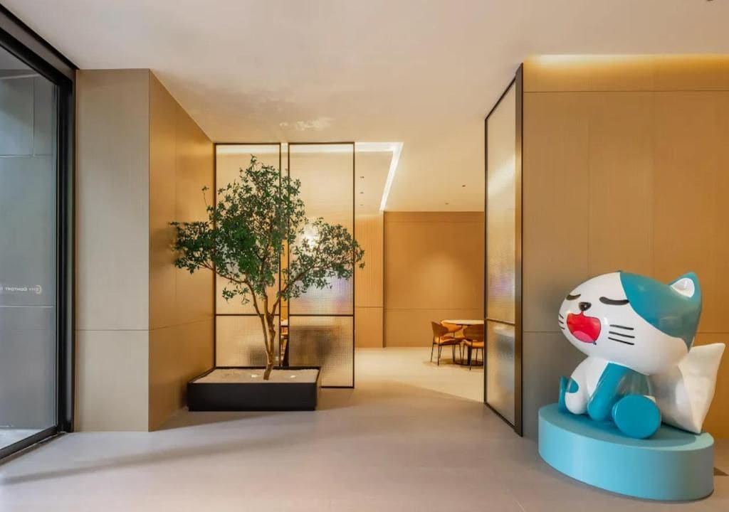 Um interior moderno com design minimalista, com área de estar, mesa pequena e cadeiras, uma escultura decorativa de gato e um vaso com planta.