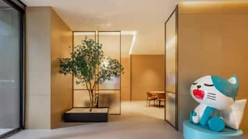 Um interior moderno com design minimalista, com área de estar, mesa pequena e cadeiras, uma escultura decorativa de gato e um vaso com planta.