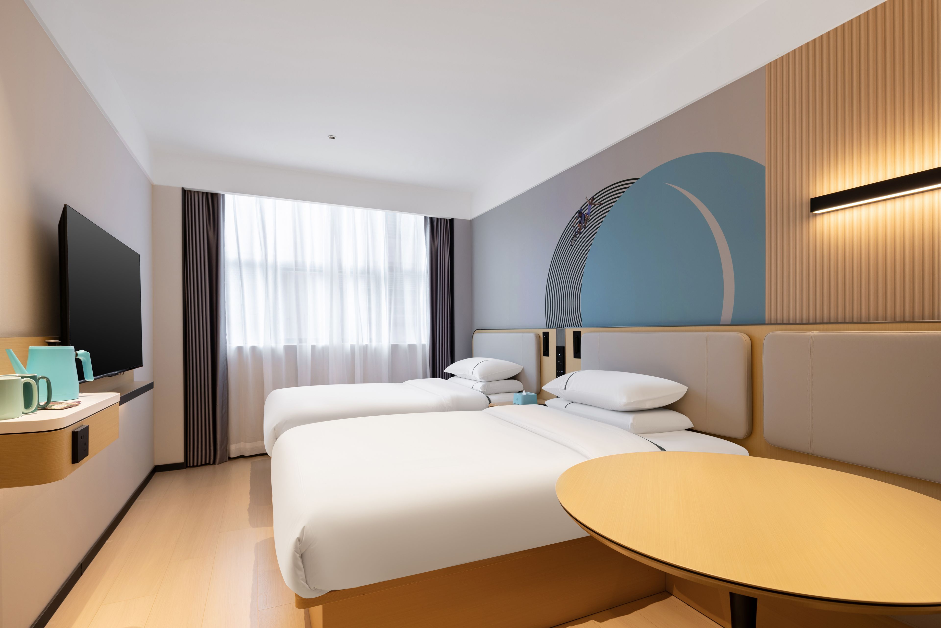Habitación de hotel con dos camas, televisión, cafetera y una mesa redonda.