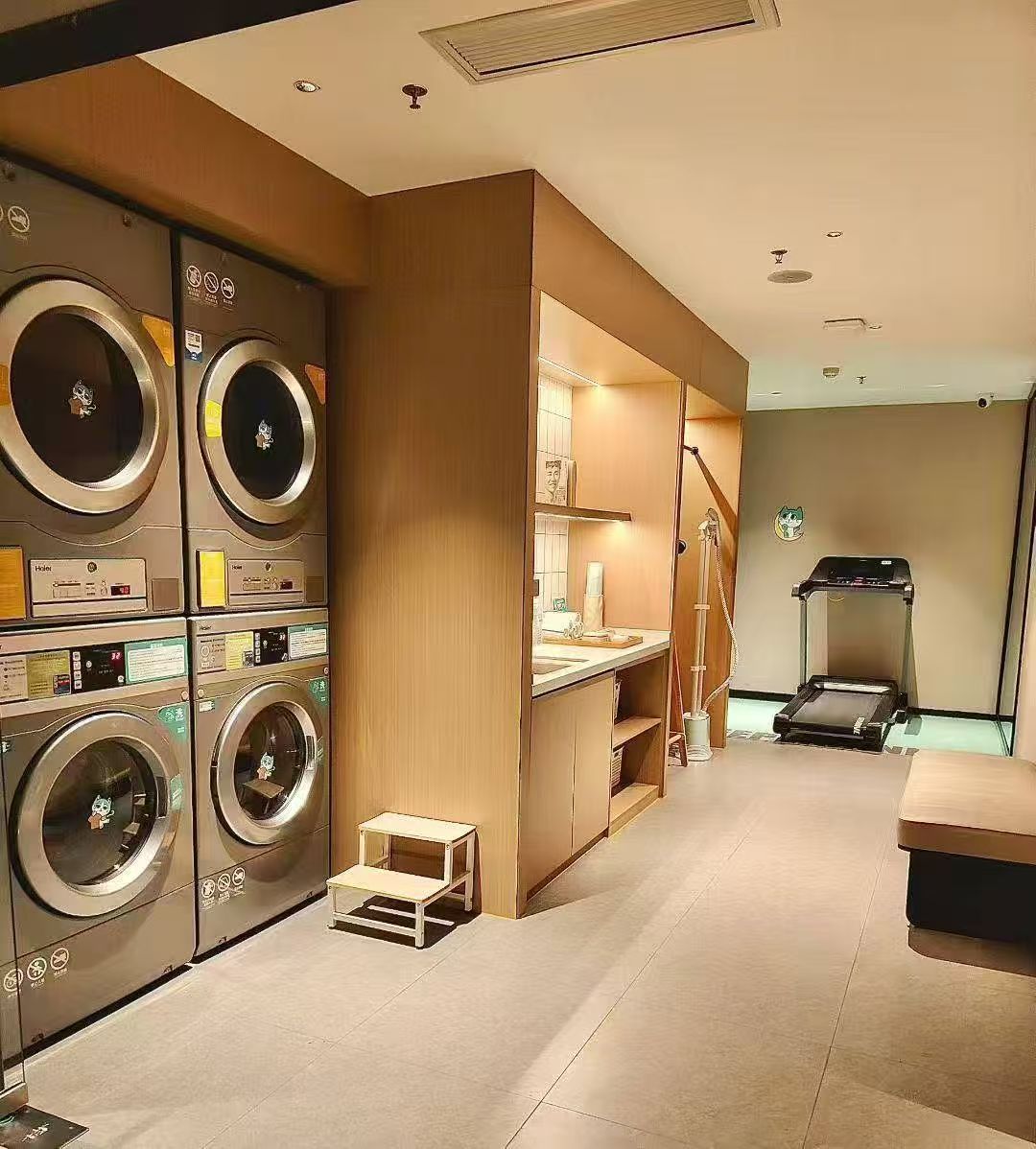 A laundry room with multiple washing machines, a small table, and a treadmill.
