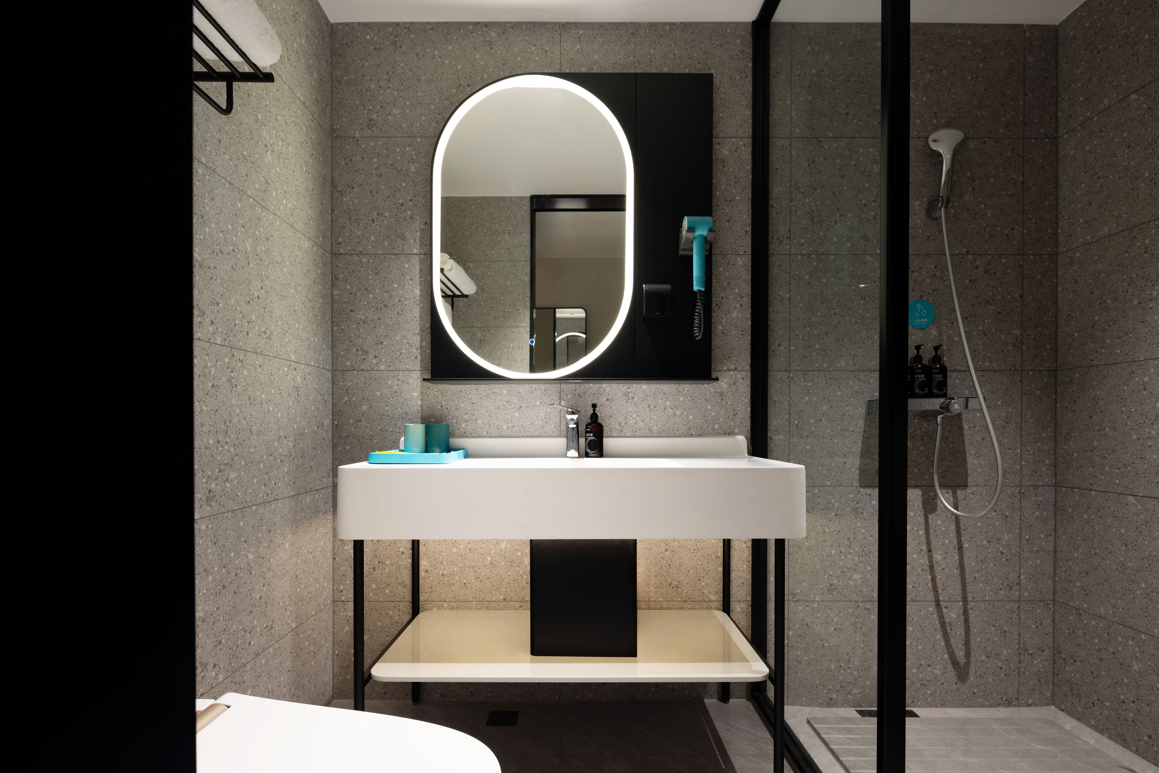 A modern bathroom with a large mirror, a white sink, and a shower.