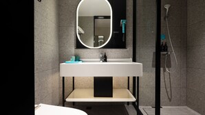 A modern bathroom with a large oval mirror, a white sink, and a shower area. - City Comfort Inn (Guangzhou)