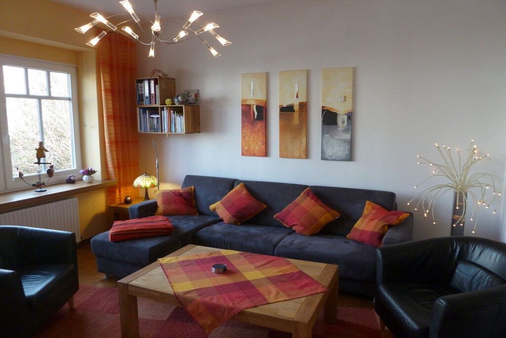 A living room with a sofa, two armchairs, a coffee table, and a bookshelf.
