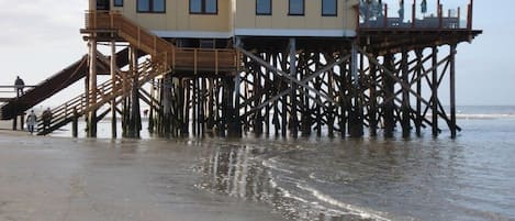 A wooden pier structure with a building on top, extending into the water.