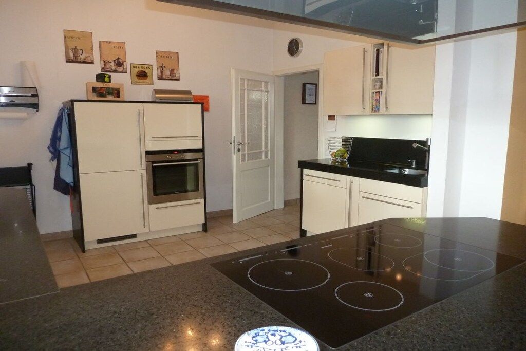 A modern kitchen with a built-in oven, a black induction cooktop, and white cabinetry.