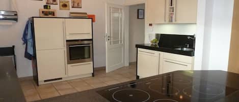 Una cocina moderna con horno empotrado, placa de inducción negra y muebles de cocina blancos.