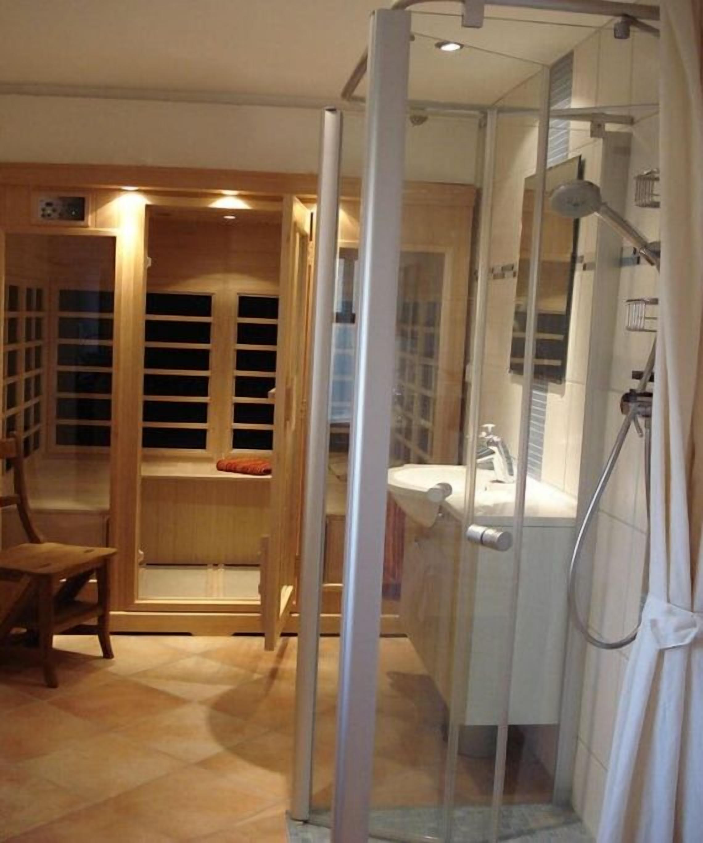 Un baño con cabina de ducha de vidrio, un banco de madera y un banco empotrado con espacio de almacenamiento.