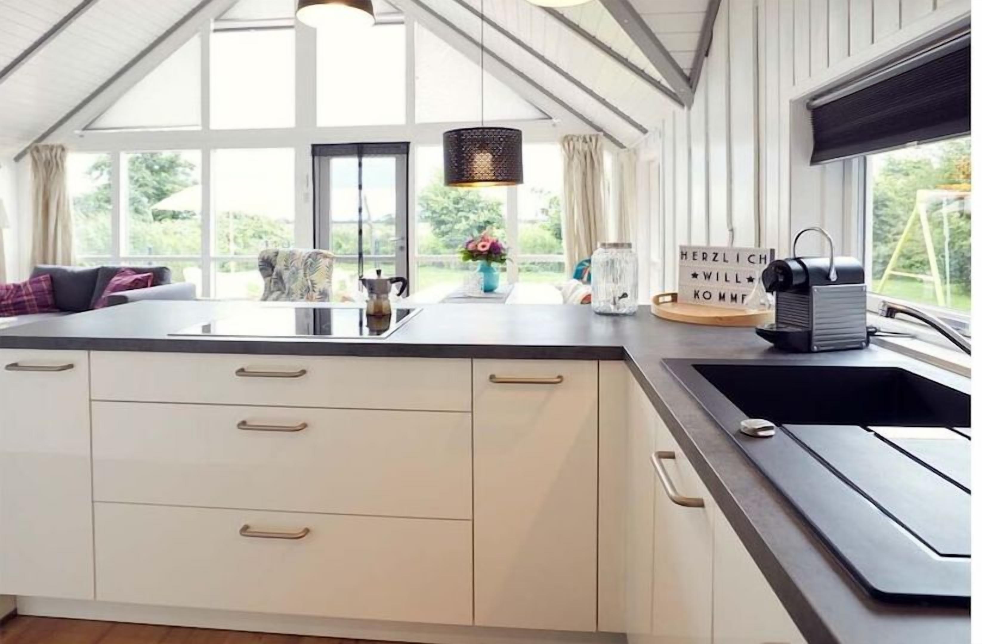 A modern kitchen with a large island, a sink, and a view of the outdoors.