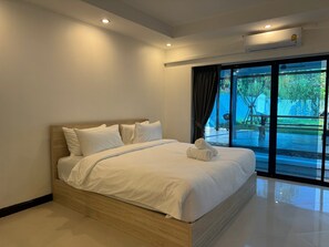 A modern bedroom with a large bed, a ceiling light, and a view of an outdoor area through a glass door. - Pratumnak 6 Pool Villa Pattaya (Pattaya City)