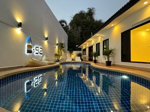 A swimming pool with tiled flooring, surrounded by walls with illuminated numbers and outdoor seating. - Pratumnak 6 Pool Villa Pattaya (Pattaya City)