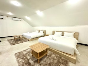 Un dormitorio moderno con dos camas, una mesita pequeña y suelo alfombrado.