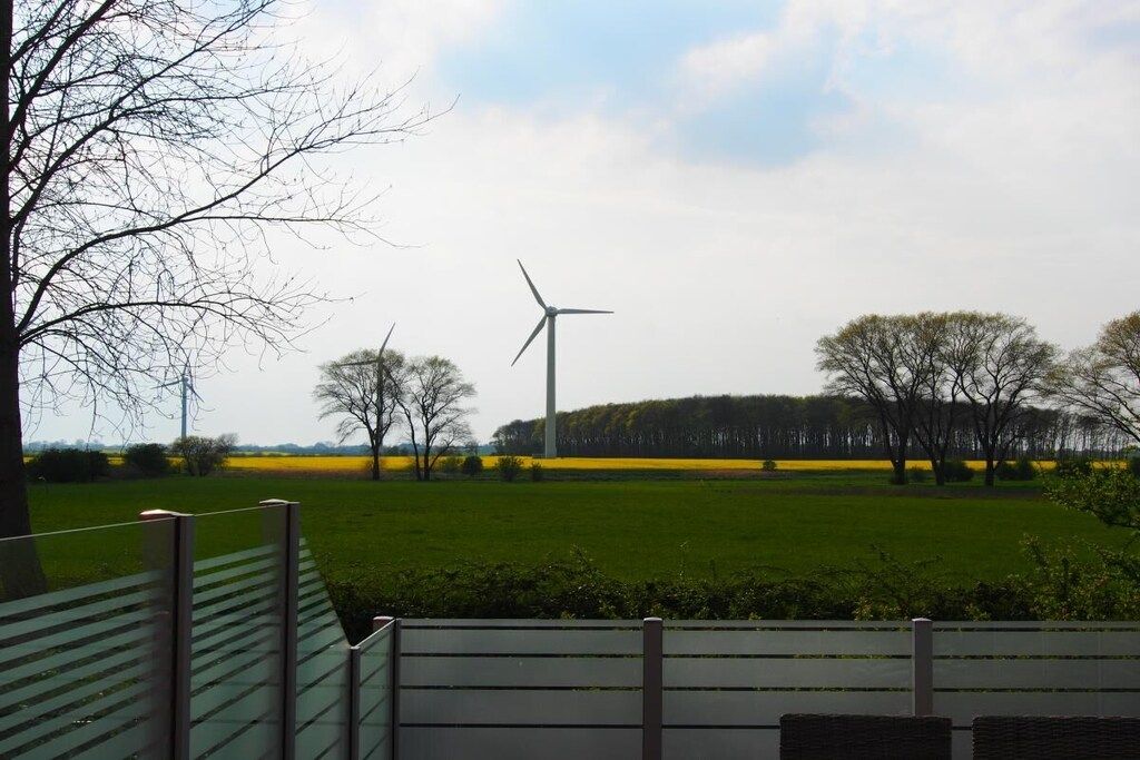 A grassy field with a wind turbine and trees.