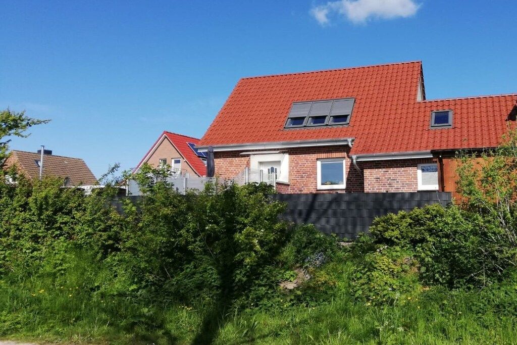 A two-story house with a red-tiled roof, brick walls, and a small window on the upper floor.