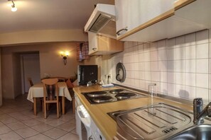 Une cuisine compacte équipée d’une cuisinière, d’un évier et d’un coin repas avec des chaises et une table.