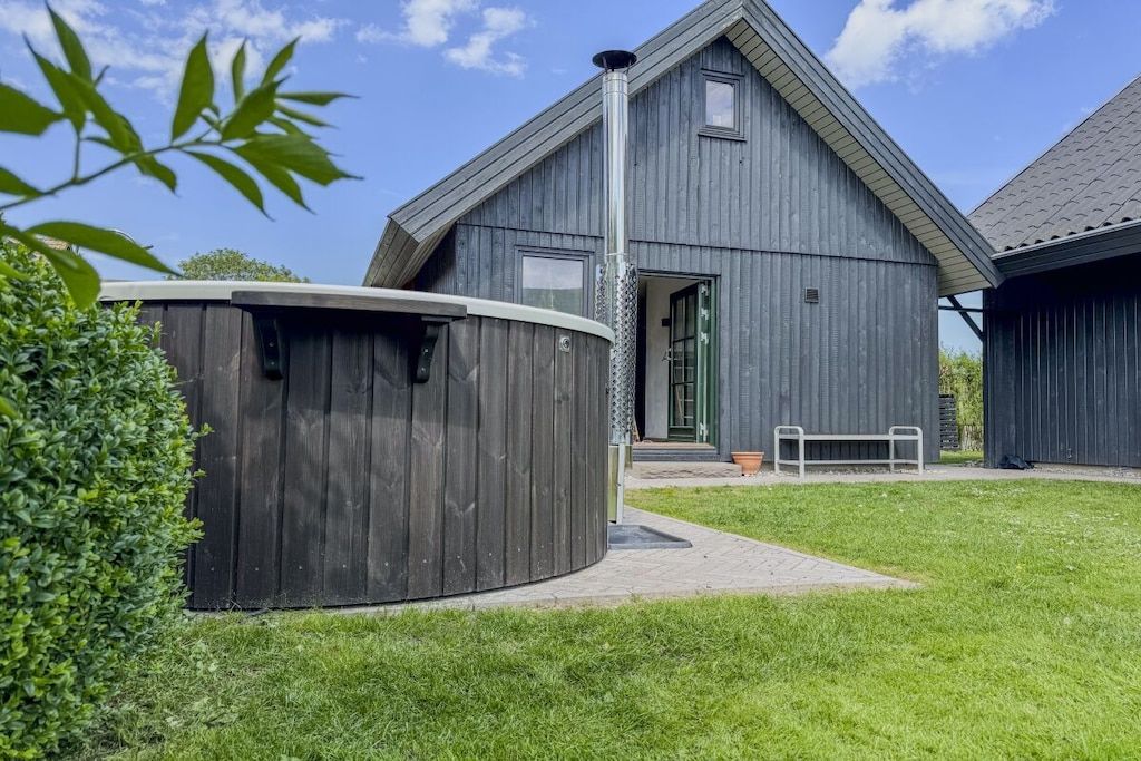 Un bâtiment moderne doté d’un toit en pente, d’une grande structure cylindrique et d’un banc au premier plan.