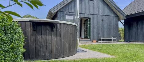 Un bâtiment moderne doté d’un toit en pente, d’une grande structure cylindrique et d’un banc au premier plan.