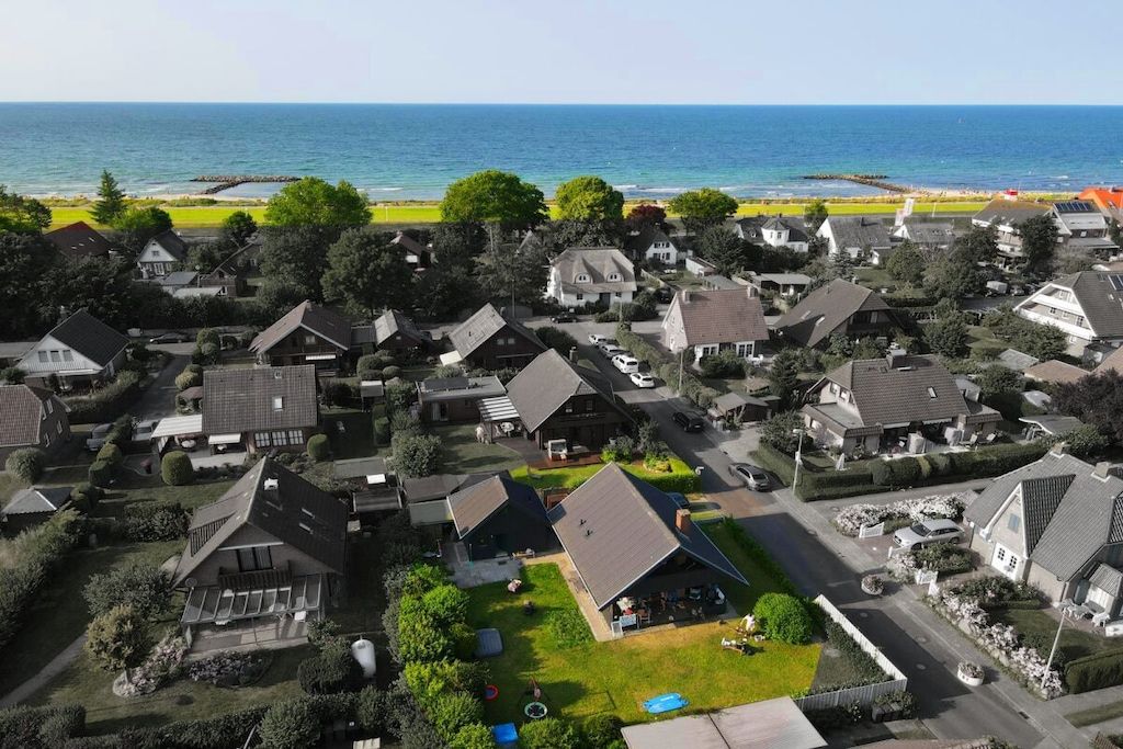 A residential area with houses, a clear view of the ocean, and a beach in the background.