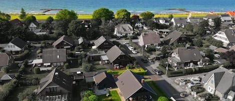 A residential area with houses, a clear view of the ocean, and a beach in the background.