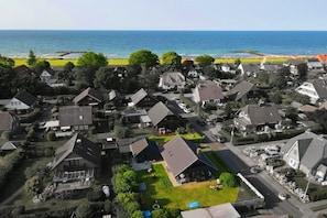 Un quartier résidentiel avec des maisons, une vue dégagée sur l’océan et une plage en arrière-plan.
