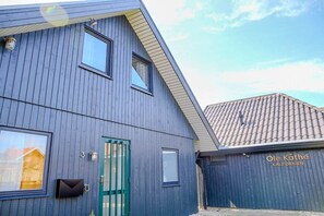 A building with a dark blue exterior, a green door, and a sign that reads 'Ole Käthe Kalifornien'. - Holiday home with 1 bedroom (Kalifornien)