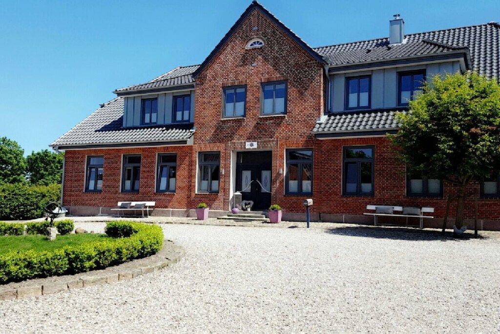 A two-story brick building with a symmetrical facade, a central entrance, and a gravel courtyard.